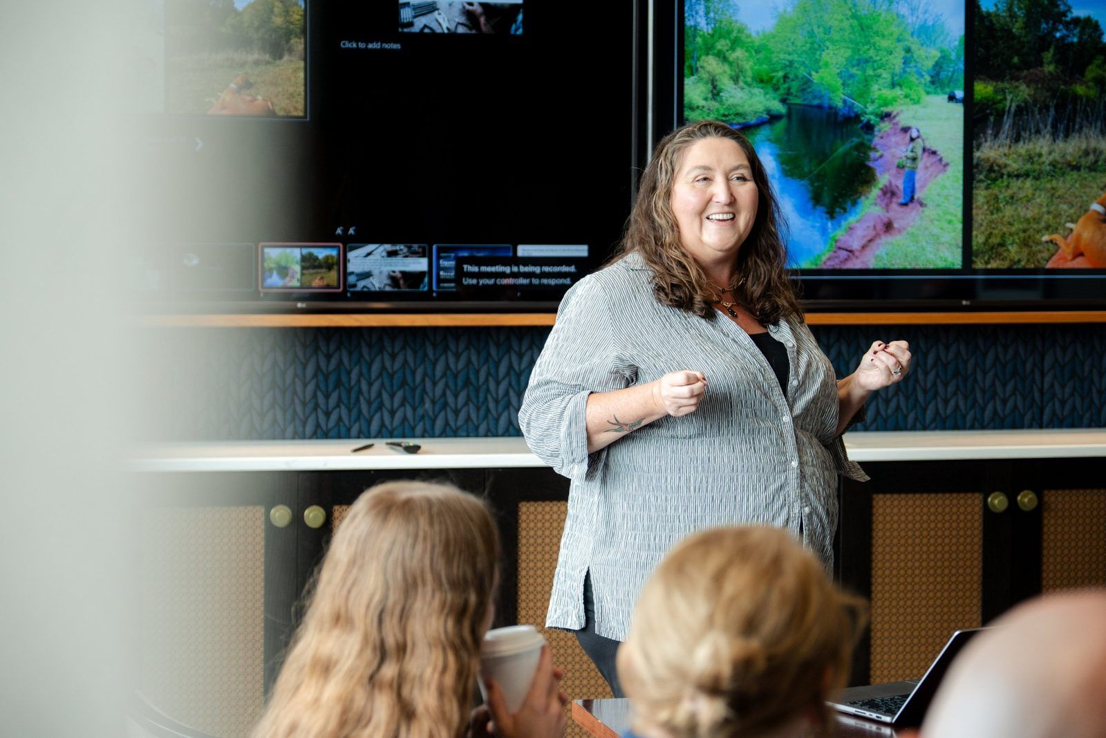 A presenter laughs while showing photos to a workshop audience
